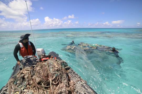 Coxswain William Reich and divers Rebecca Weible and Alika Garcia survey and find a large derelict fishing net at Kamokukamohoaliʻi (Maro Reef).