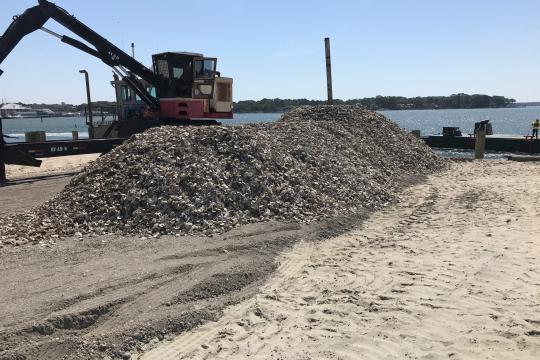 A crane is docked next to a pile of oyster shells