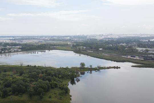 Aerial view of a lake surrounded by wetlands, with a city in the background