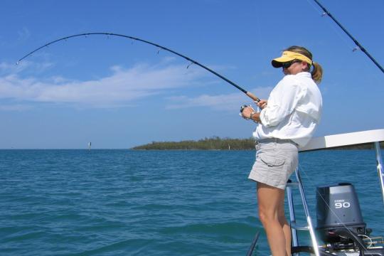 Fishing in the Gulf of Mexico, women on the stern of a boat in shorts and visor. 