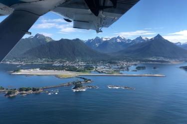 Aerial photo of Sitka and with small islands and airport in the foreground and mountains in the background. 