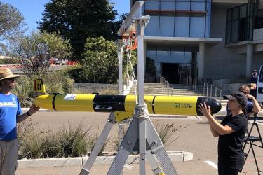 two staff calibrate glider compass in the parking lot of the science center