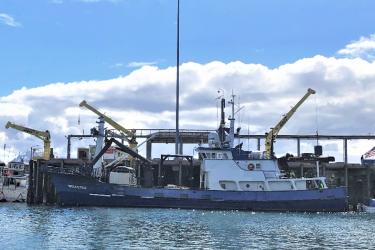 A large steel boat at port on a clear day with some clouds on the horizon. Credit: NOAA Fisheries