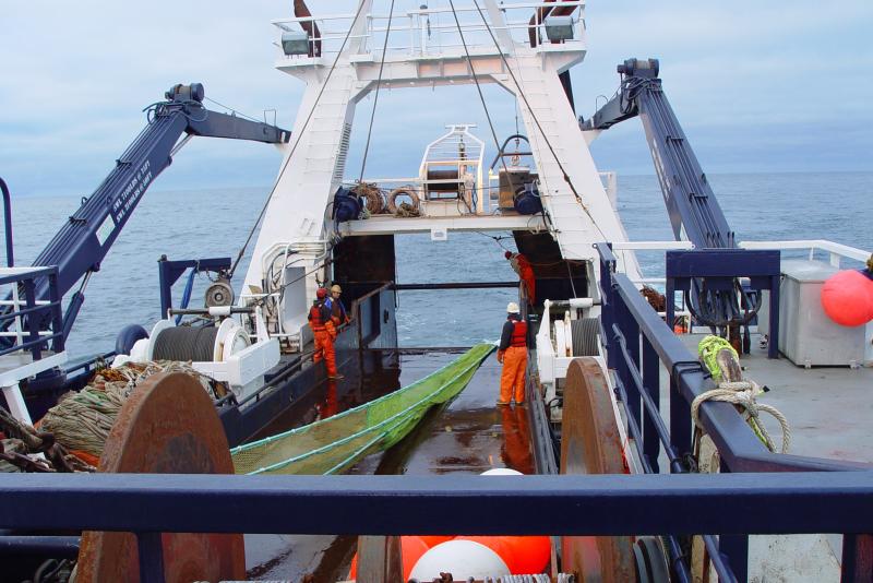 Photo of workers on a boat deck with a surface trawl net.