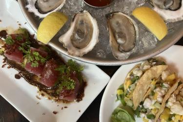 Neatly plated tuna crudo, halibut ceviche tacos, and eastern oysters, served at Row 34 restaurant.