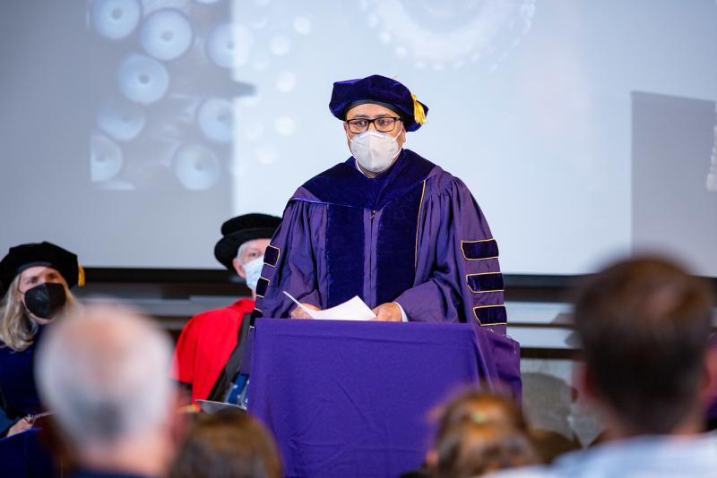 A masked Jamal Moss stands in his robe, hood, and cap to give his speech. Credit: University of Washington (used with permission by NOAA Fisheries)